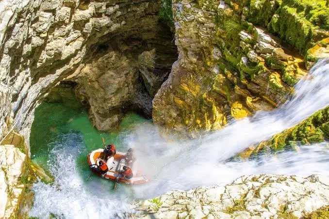 A guided raft navigating the pool beneath Peshtura Waterfall during a canyoning tour