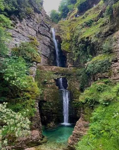 The tiered Peshtura Waterfall dropping into its turquoise pool in the Kurvelesh mountains