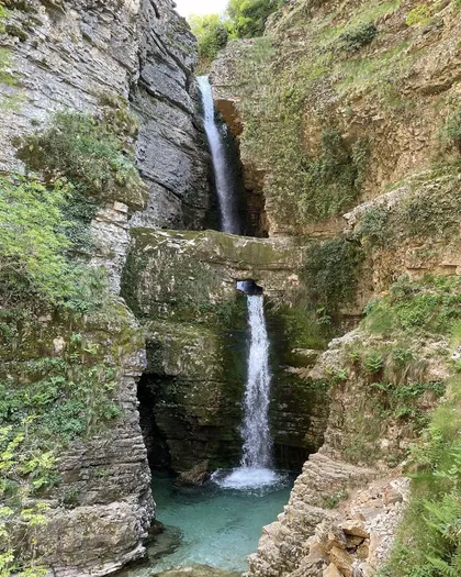 The two-tiered drop of Peshtura Waterfall flowing through a natural rock window into the pool below